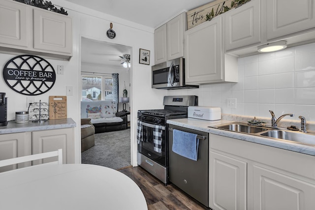 kitchen with tasteful backsplash, white cabinets, stainless steel appliances, light countertops, and a sink