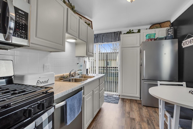 kitchen featuring decorative backsplash, appliances with stainless steel finishes, dark wood-type flooring, light countertops, and a sink