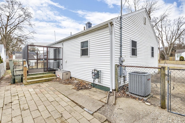 rear view of house featuring a chimney, a gate, a patio area, central AC, and fence