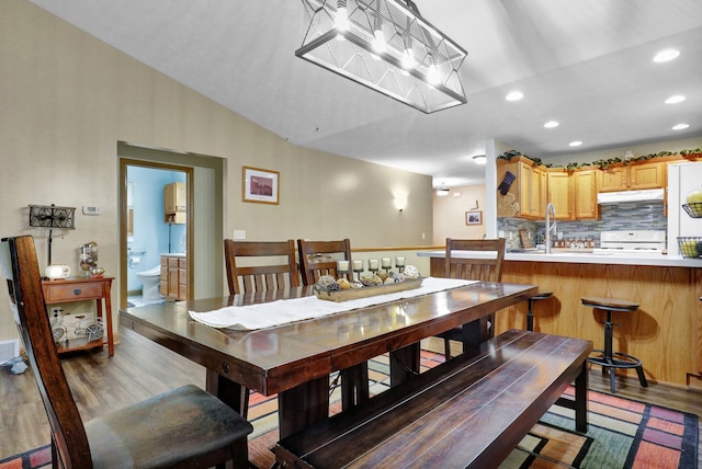 dining space with recessed lighting, vaulted ceiling, and wood finished floors