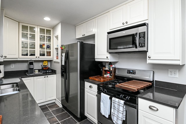 kitchen featuring appliances with stainless steel finishes, white cabinetry, glass insert cabinets, and a sink