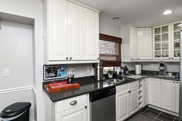 kitchen with dark countertops, white cabinetry, dishwasher, and a sink