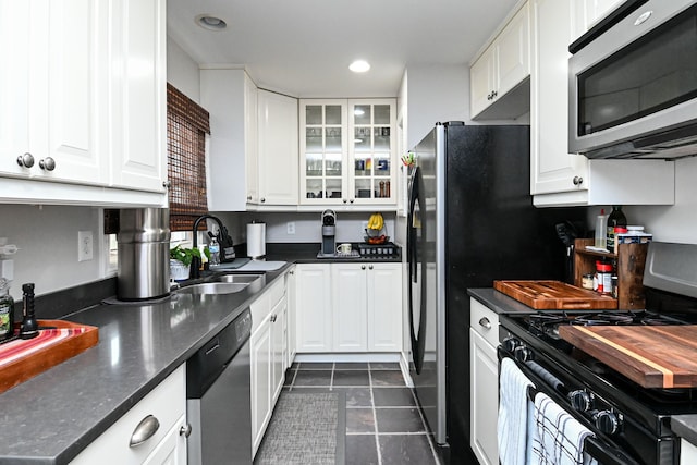 kitchen with dark countertops, white cabinetry, a sink, gas range, and dishwasher