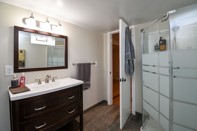 full bath featuring a stall shower, wood finished floors, vanity, and baseboards