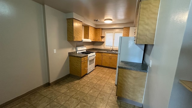 kitchen featuring a sink, baseboards, dark countertops, and white gas range