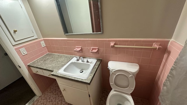 bathroom featuring tile patterned flooring, a wainscoted wall, toilet, vanity, and tile walls