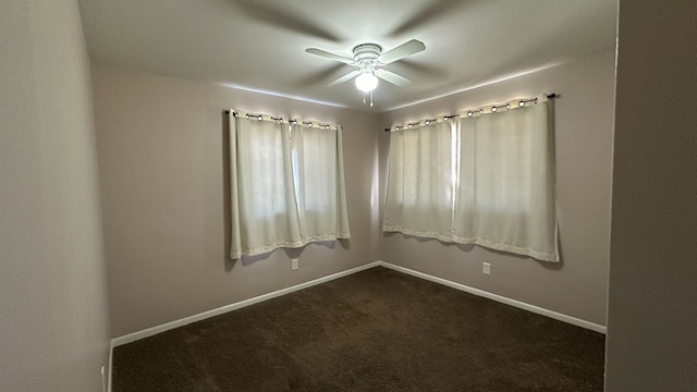 unfurnished room with a ceiling fan, baseboards, and dark colored carpet