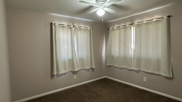 unfurnished room with dark carpet, a ceiling fan, and baseboards