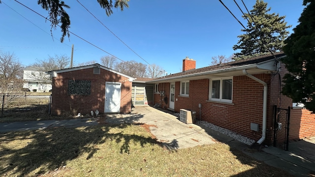 back of property featuring brick siding, fence, central air condition unit, a chimney, and a yard