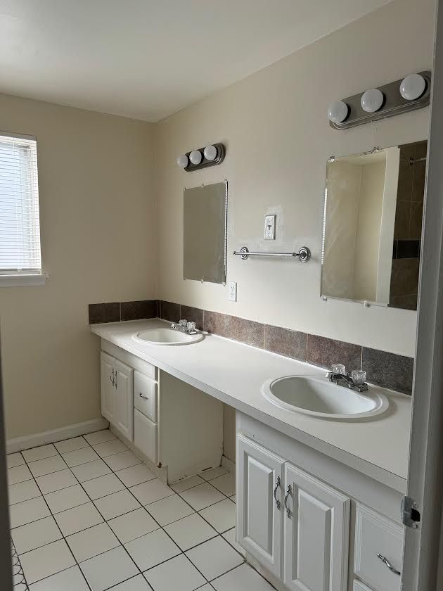 full bathroom featuring double vanity, a sink, and tile patterned floors