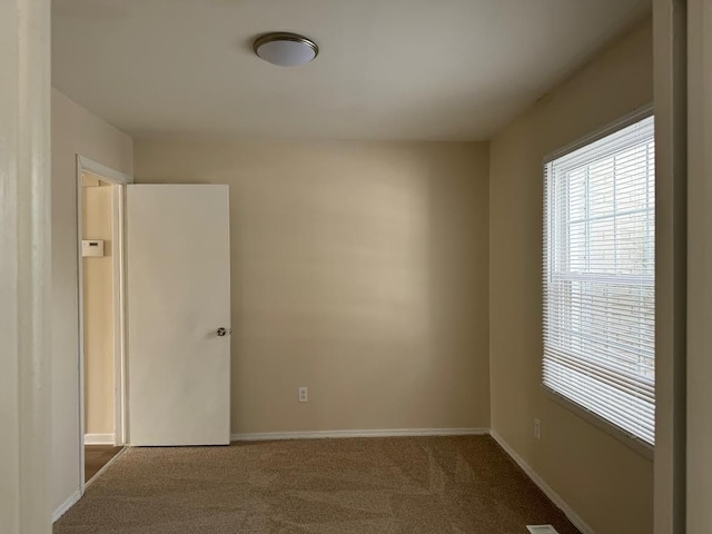 unfurnished room with baseboards and carpet flooring