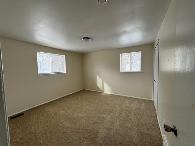 empty room featuring carpet floors, plenty of natural light, and visible vents