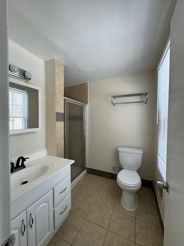 full bath with tile patterned flooring, toilet, vanity, a shower stall, and a wall mounted air conditioner