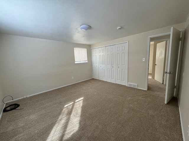 unfurnished bedroom with carpet, a closet, visible vents, and baseboards