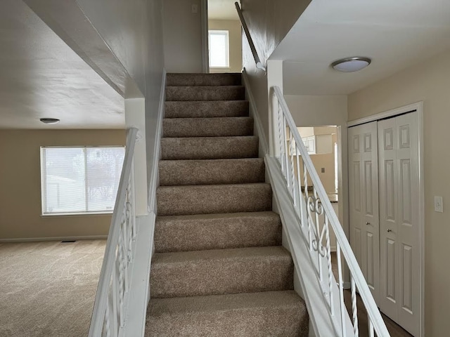 staircase with plenty of natural light, carpet, visible vents, and baseboards