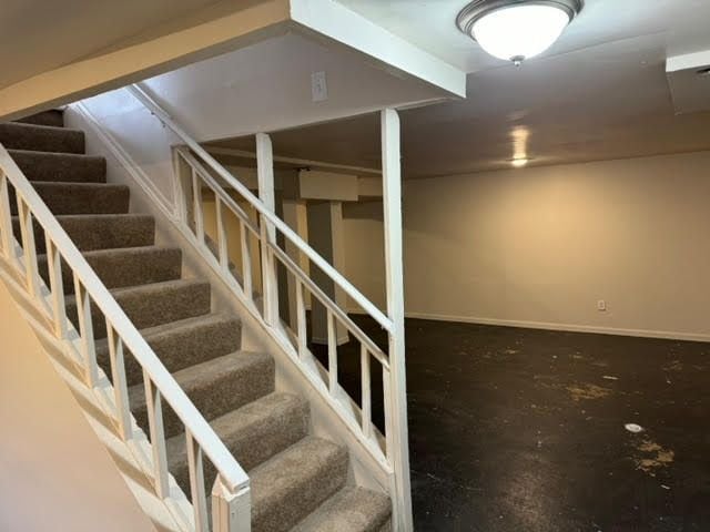 finished basement with stairway and baseboards