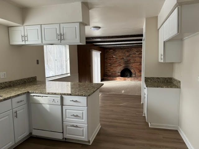 kitchen featuring dishwasher, a peninsula, dark wood-style flooring, and white cabinetry