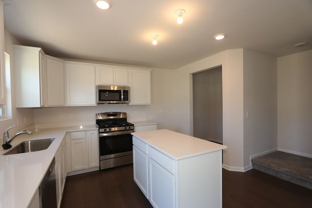 kitchen with white cabinets, dark wood-style floors, appliances with stainless steel finishes, light countertops, and a sink