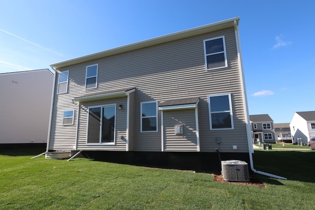 rear view of property featuring central AC and a yard