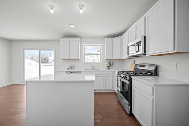 kitchen featuring a sink, dark wood finished floors, stainless steel appliances, white cabinets, and light countertops