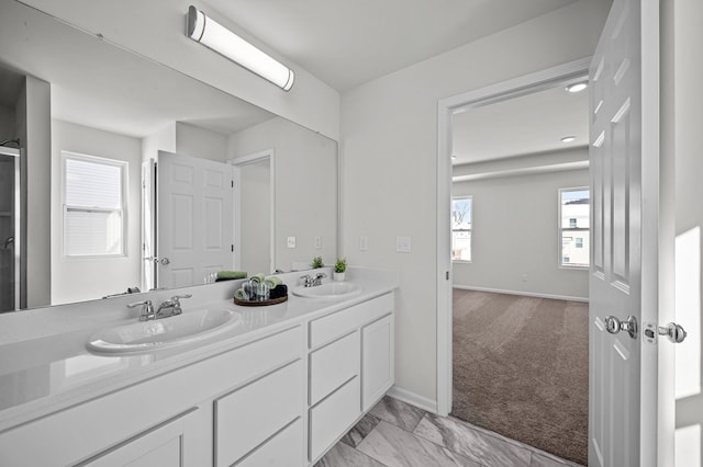 full bathroom with double vanity, baseboards, marble finish floor, and a sink