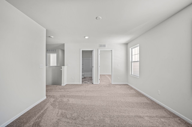 unfurnished room featuring baseboards, visible vents, and light carpet