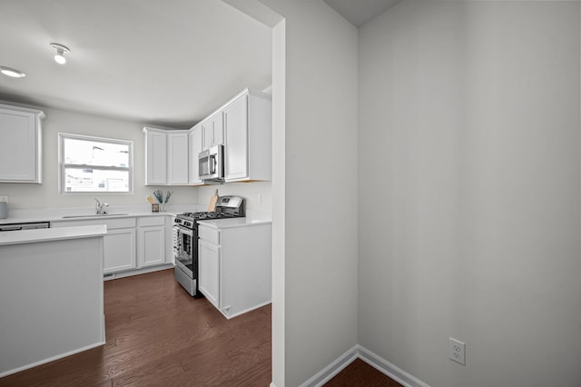 kitchen featuring dark wood-type flooring, a sink, white cabinetry, appliances with stainless steel finishes, and light countertops