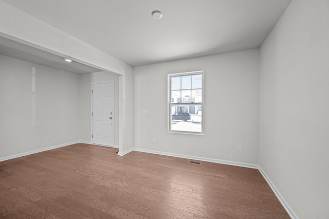 spare room with visible vents, baseboards, and dark wood-type flooring