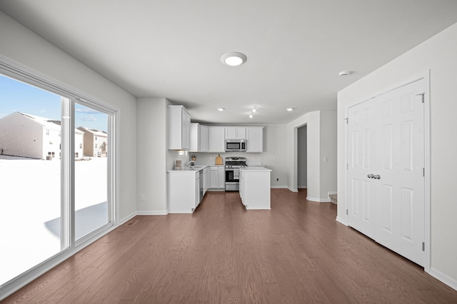 kitchen featuring baseboards, dark wood finished floors, light countertops, white cabinets, and appliances with stainless steel finishes