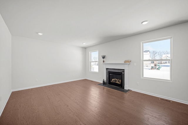 unfurnished living room featuring baseboards, visible vents, recessed lighting, dark wood-style flooring, and a glass covered fireplace