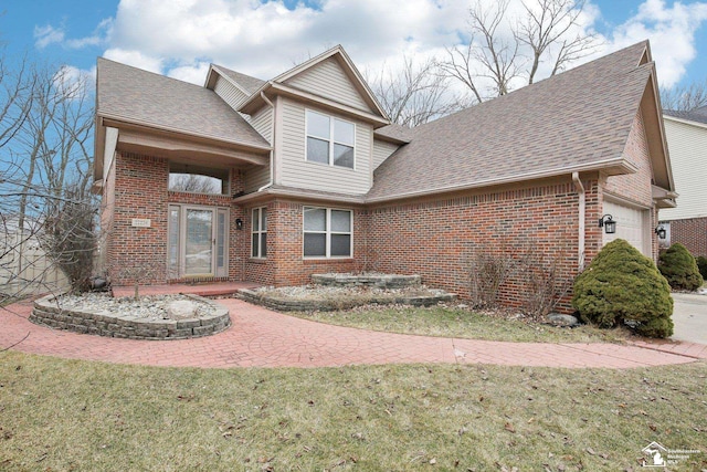 view of front of property featuring an attached garage, roof with shingles, a front lawn, and brick siding