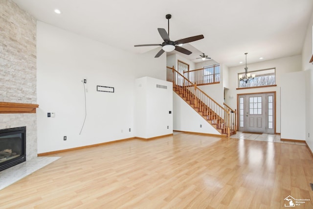 unfurnished living room featuring baseboards, visible vents, wood finished floors, stairs, and a stone fireplace