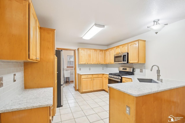 kitchen featuring light tile patterned floors, backsplash, appliances with stainless steel finishes, a sink, and a peninsula