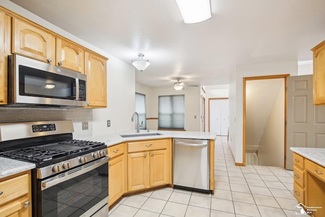 kitchen with stainless steel appliances, light countertops, a sink, and a peninsula