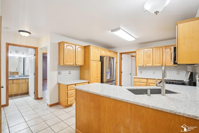 kitchen with stainless steel appliances, light tile patterned flooring, a sink, light stone countertops, and a peninsula