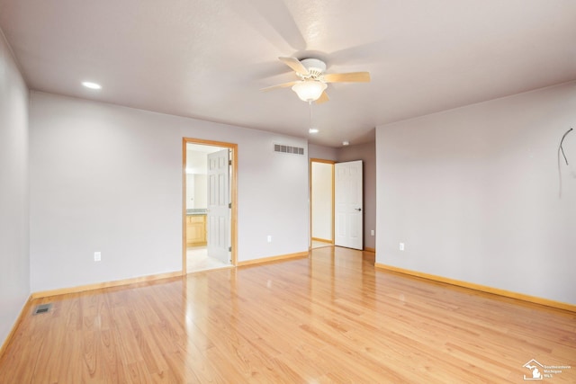 unfurnished room with a ceiling fan, visible vents, light wood-style flooring, and baseboards