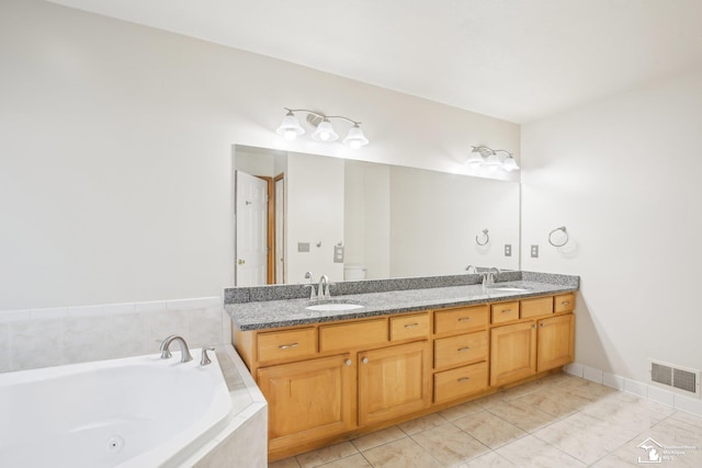 full bathroom with double vanity, a tub with jets, a sink, and visible vents