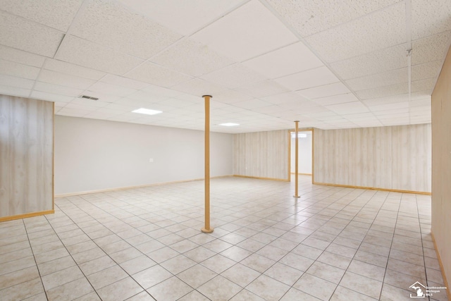 finished basement featuring light tile patterned floors, a drop ceiling, visible vents, and baseboards