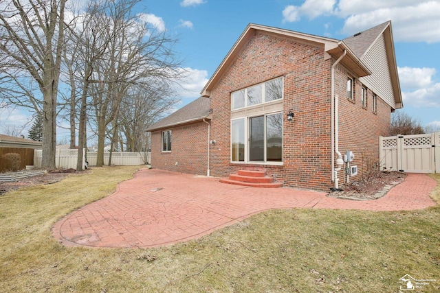 rear view of property featuring brick siding, a yard, entry steps, a patio area, and fence