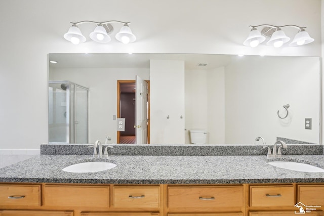 full bathroom with double vanity, a stall shower, a sink, and toilet