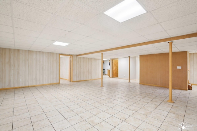 finished basement with a drop ceiling and wooden walls