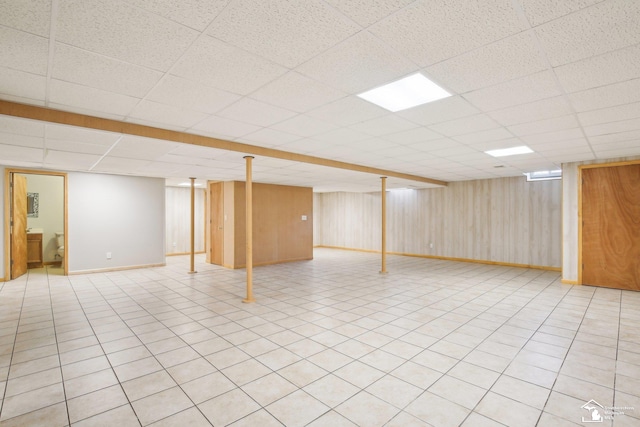 finished basement featuring a paneled ceiling and baseboards