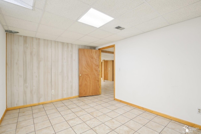 unfurnished room with a paneled ceiling, baseboards, and visible vents