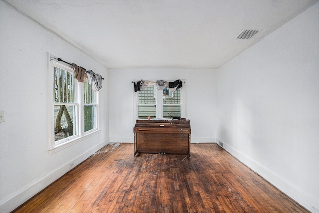 unfurnished room with wood-type flooring, visible vents, and baseboards