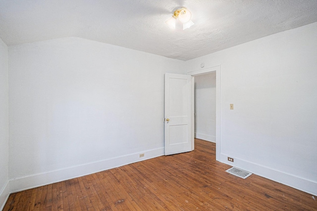 empty room with wood-type flooring, visible vents, and baseboards