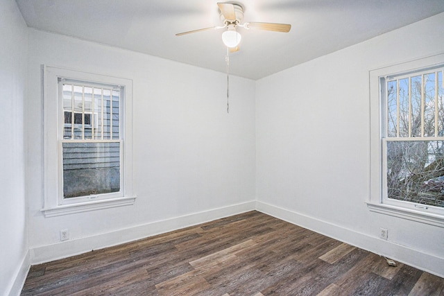 unfurnished room with dark wood finished floors, plenty of natural light, and baseboards