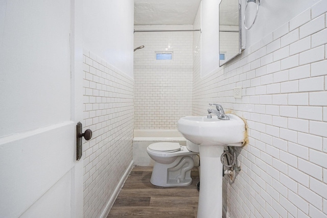 full bathroom with toilet, tile walls, tiled shower / bath, and wood finished floors