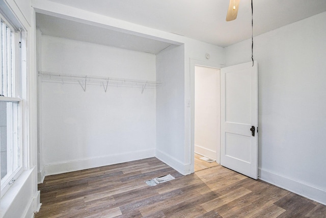 unfurnished bedroom with ceiling fan, wood finished floors, visible vents, baseboards, and a closet