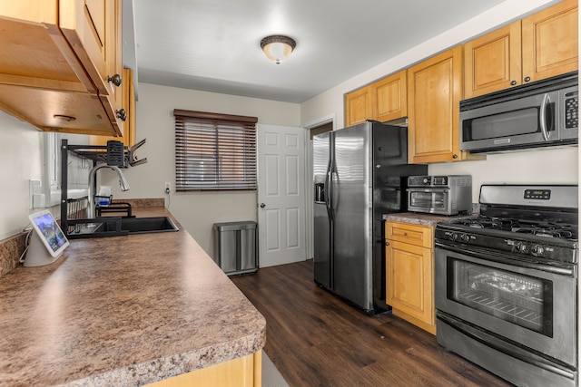 kitchen featuring stainless steel appliances, a toaster, a sink, and dark wood-style floors