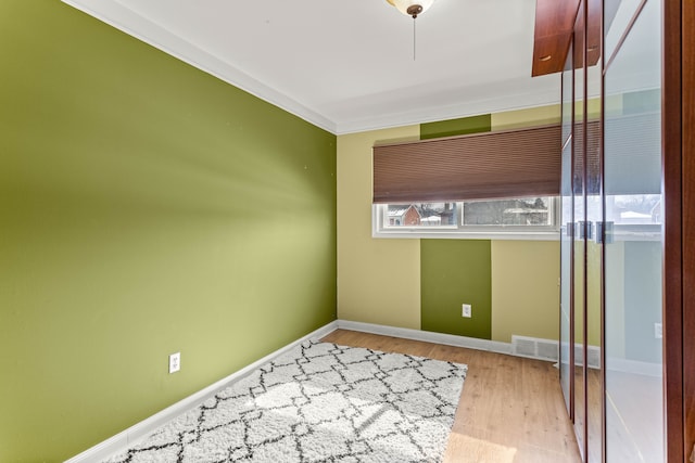 spare room featuring wood finished floors, visible vents, and baseboards